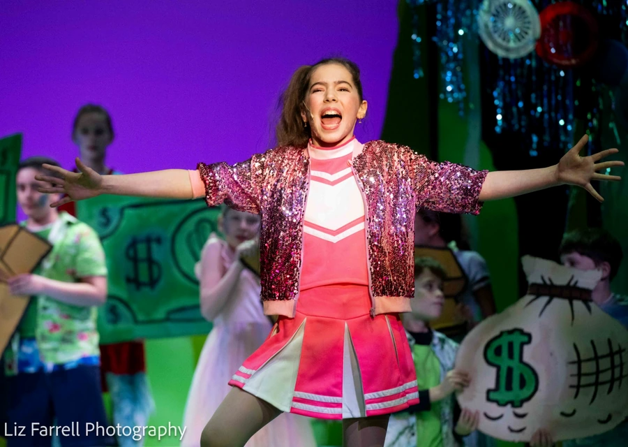 Samara performing on stage in a pink sequined costume